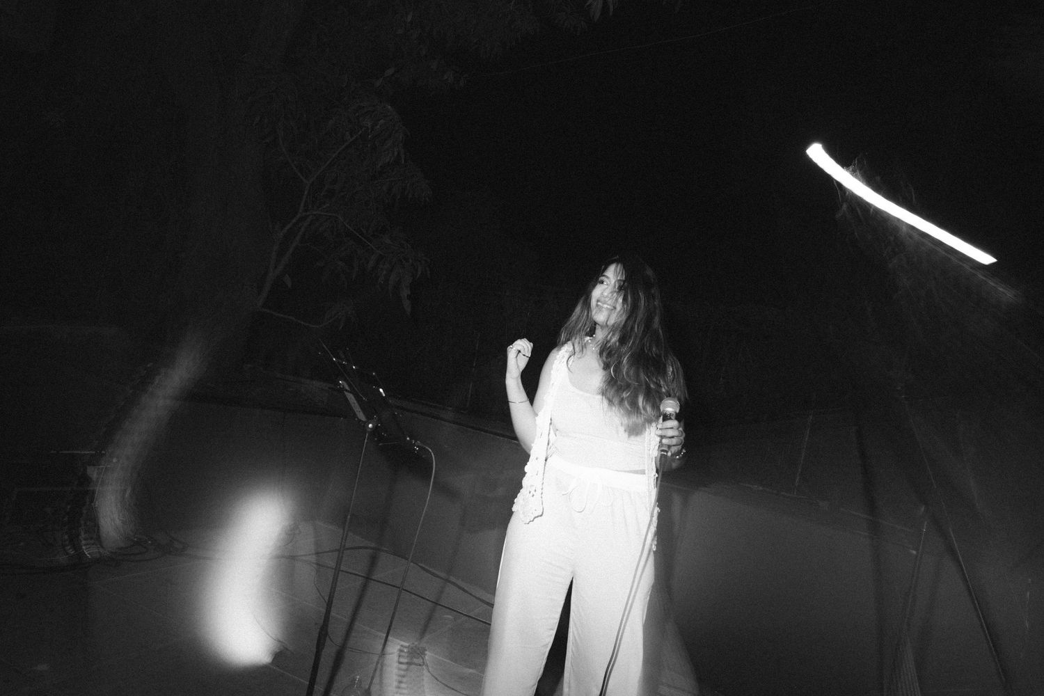 Wedding performer in white attire singing on stage with dramatic lighting by a wedding photographer in London & Birmingham.