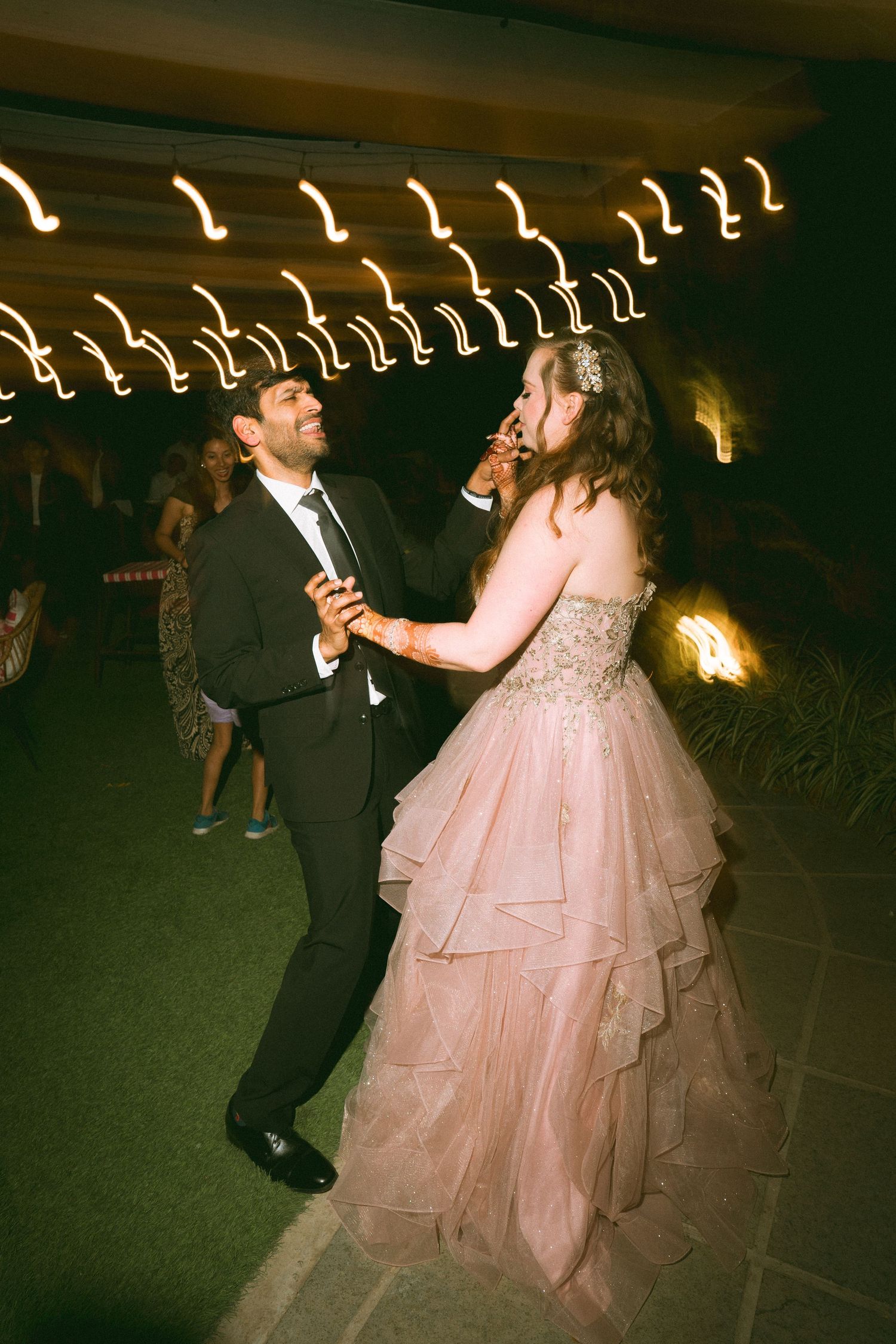Couple dancing together at a wedding reception under string lights by a wedding photographer in London & Birmingham.