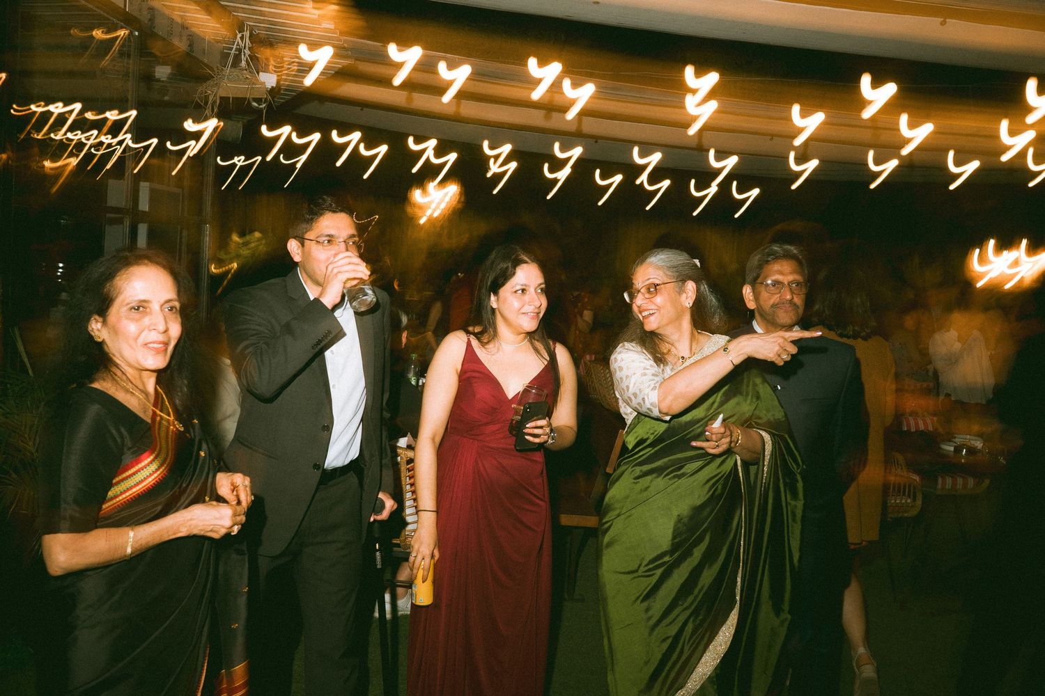 Elegantly dressed wedding guests mingling at a formal event under warm lighting by a wedding photographer in London & Birmingham.