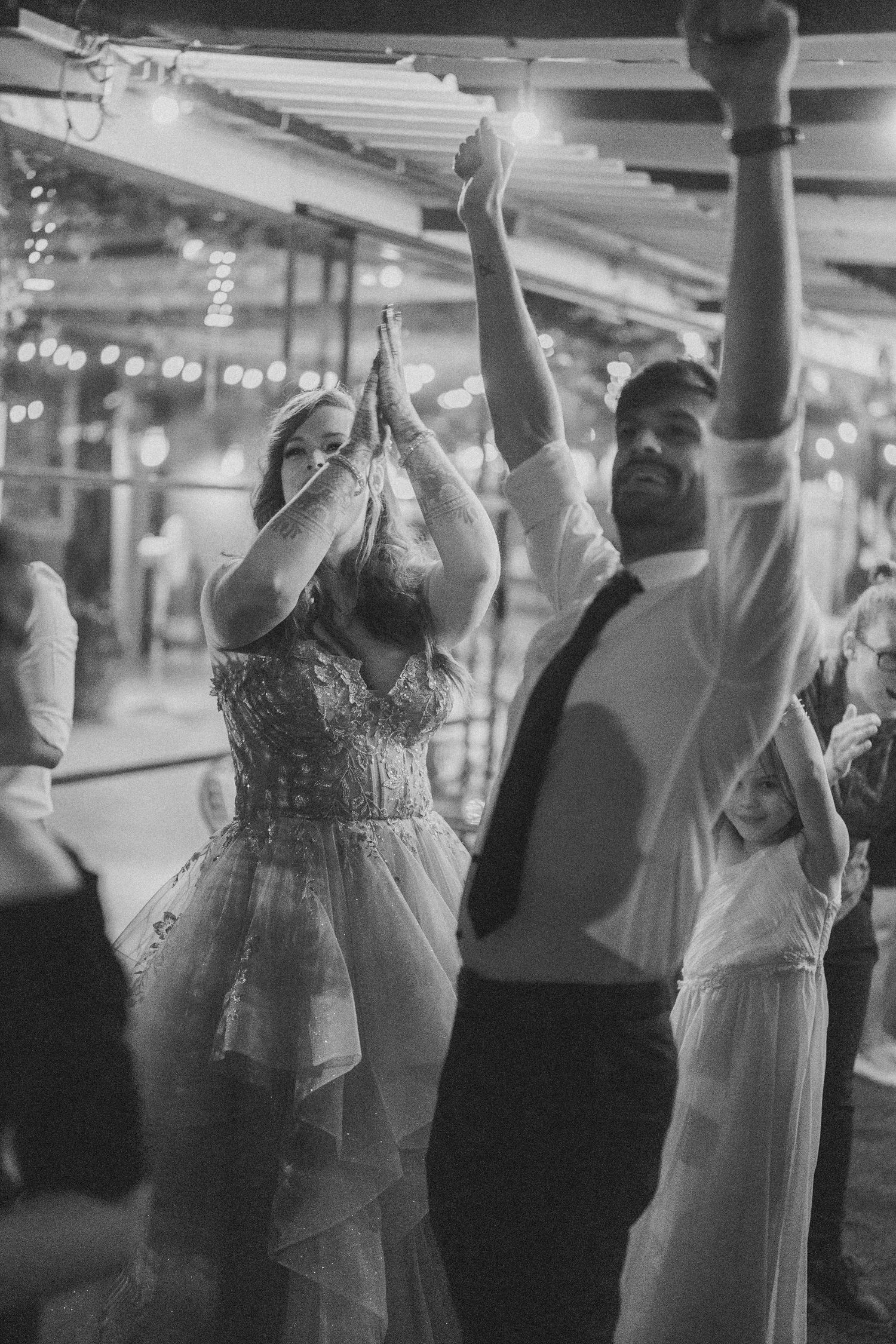 Black & white wedding reception shot of guests raising arms on the dance floor by a wedding photographer in London & Birmingham.