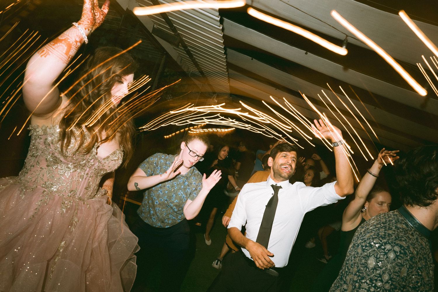 Motion-blurred wedding guests dancing energetically under venue lighting by a wedding photographer in London & Birmingham