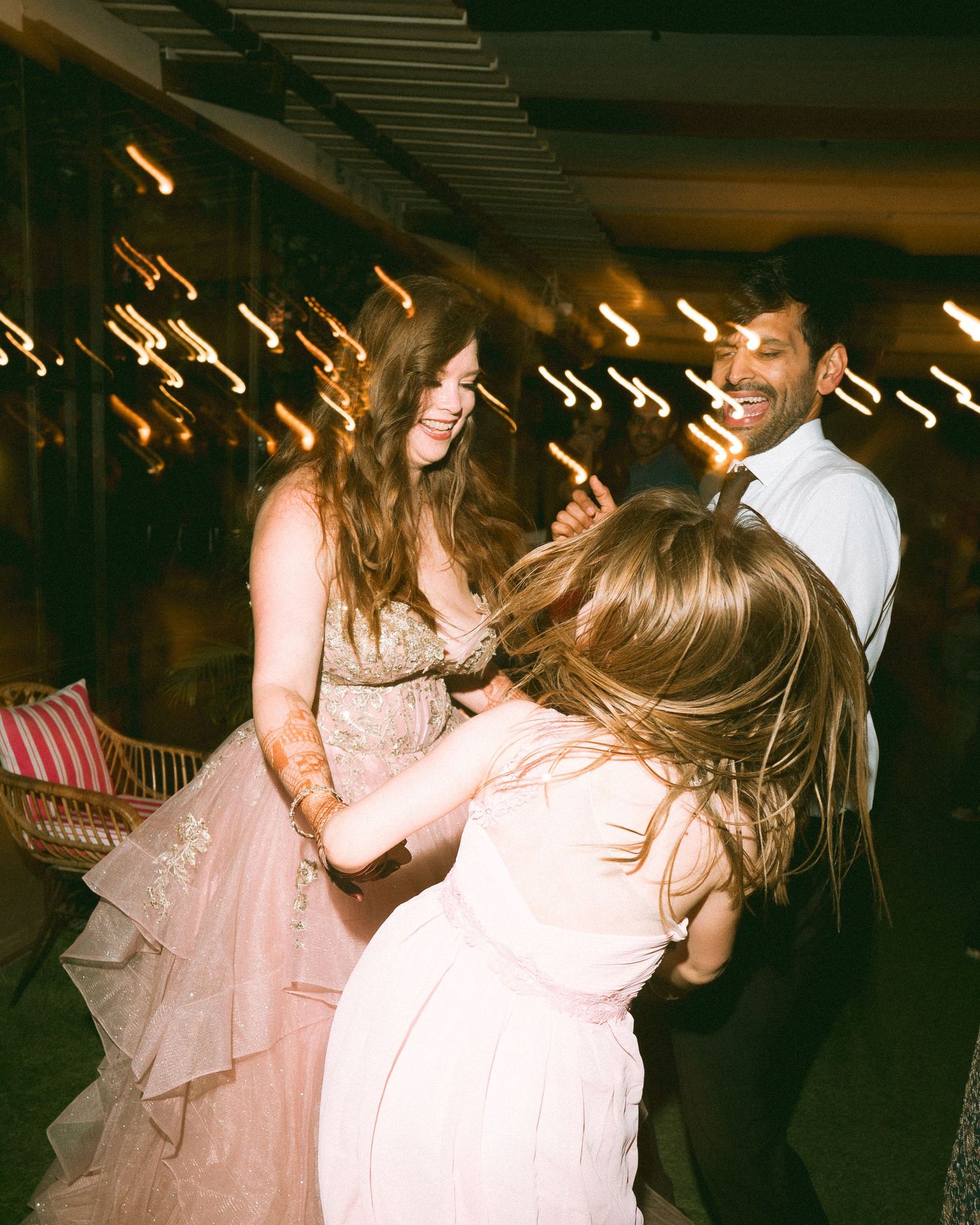 Joyful wedding reception dance with pink ruffled gown under festive lighting by a wedding photographer in London & Birmingham.