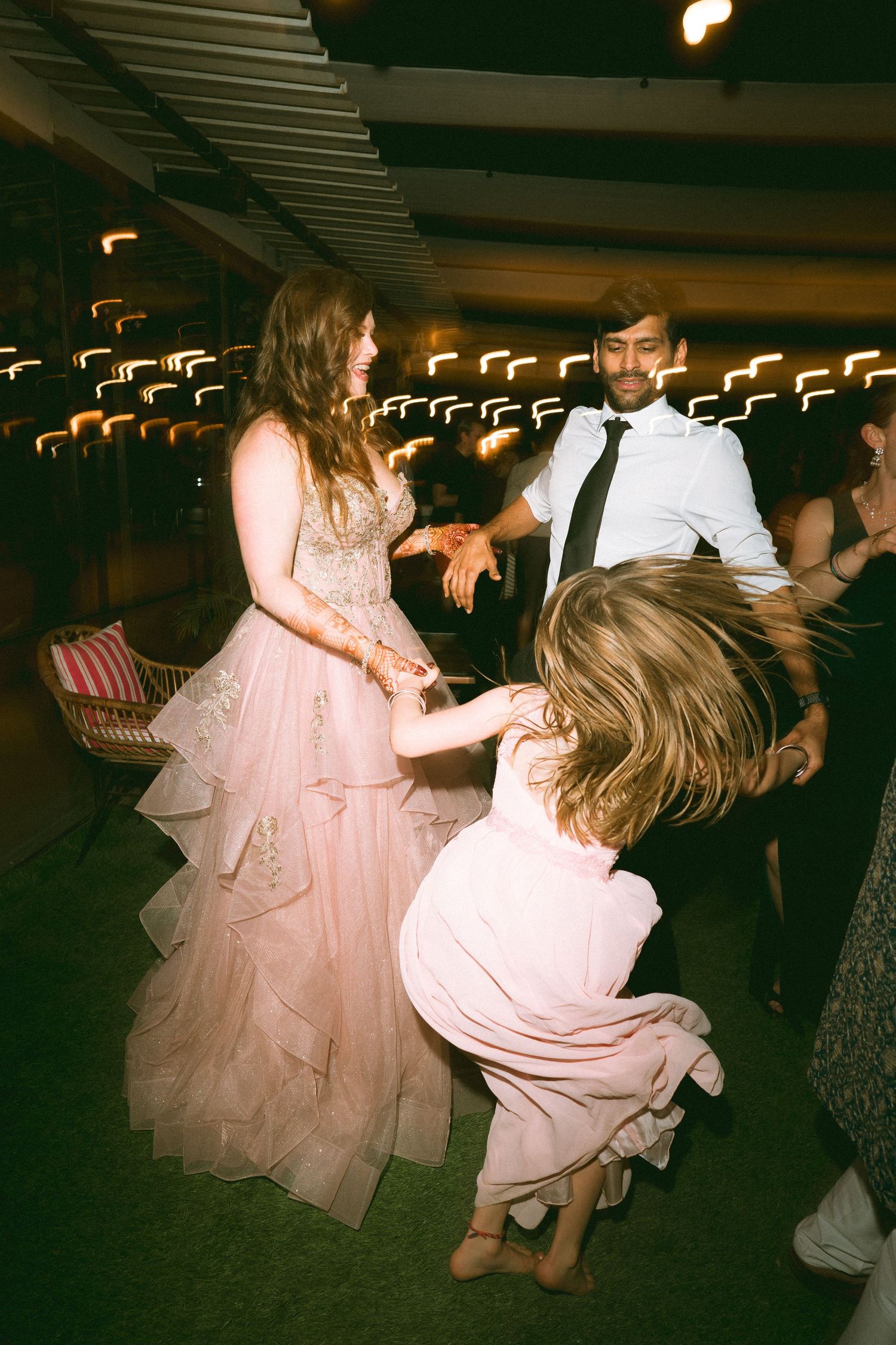 Energetic wedding dance with flowing pink dresses under ambient lighting by a wedding photographer in London & Birmingham.