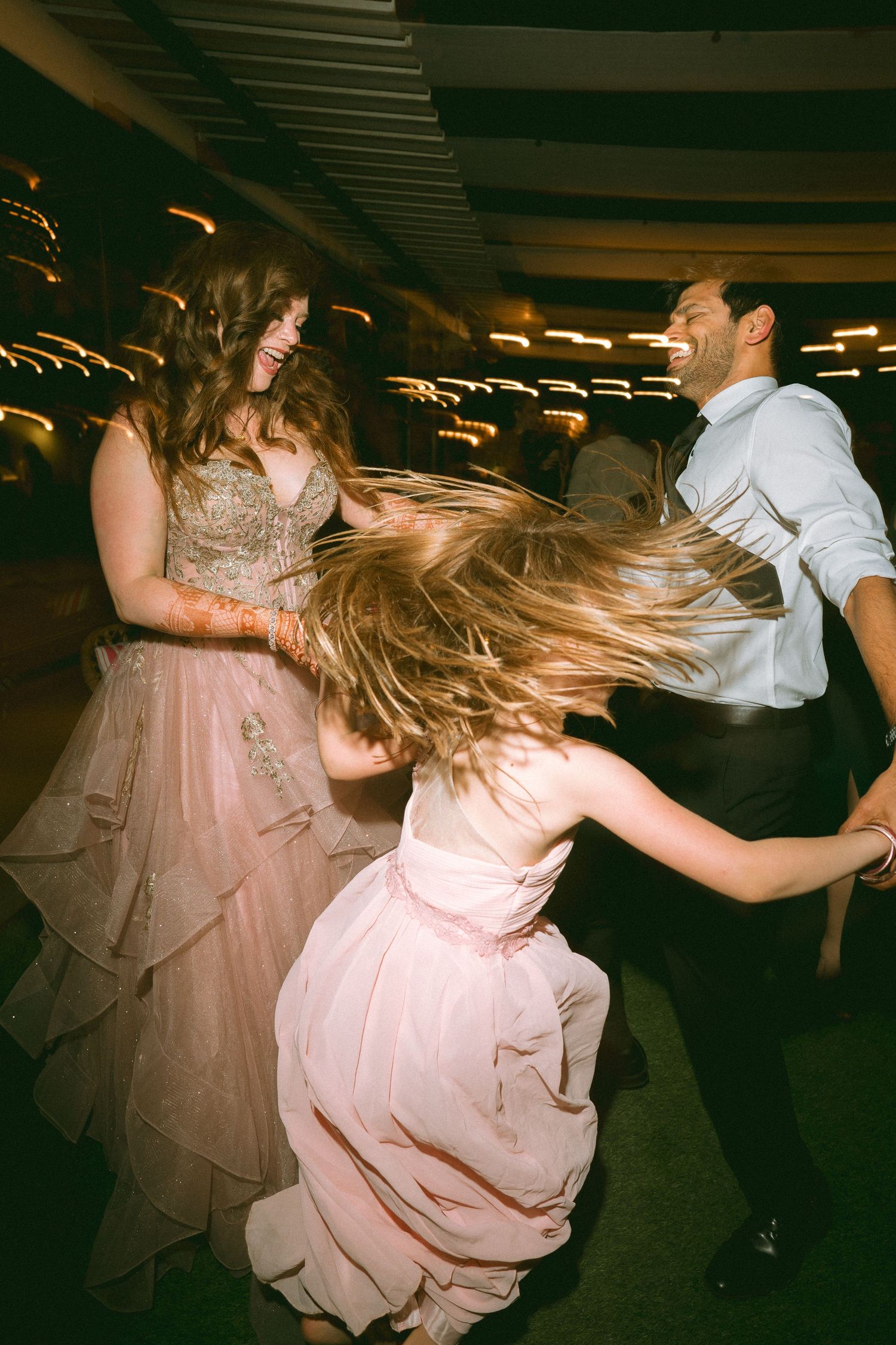 Dynamic wedding dance with twirling dresses under vintage-style lighting by a wedding photographer in Sydney, Gold Coast & Brisbane.