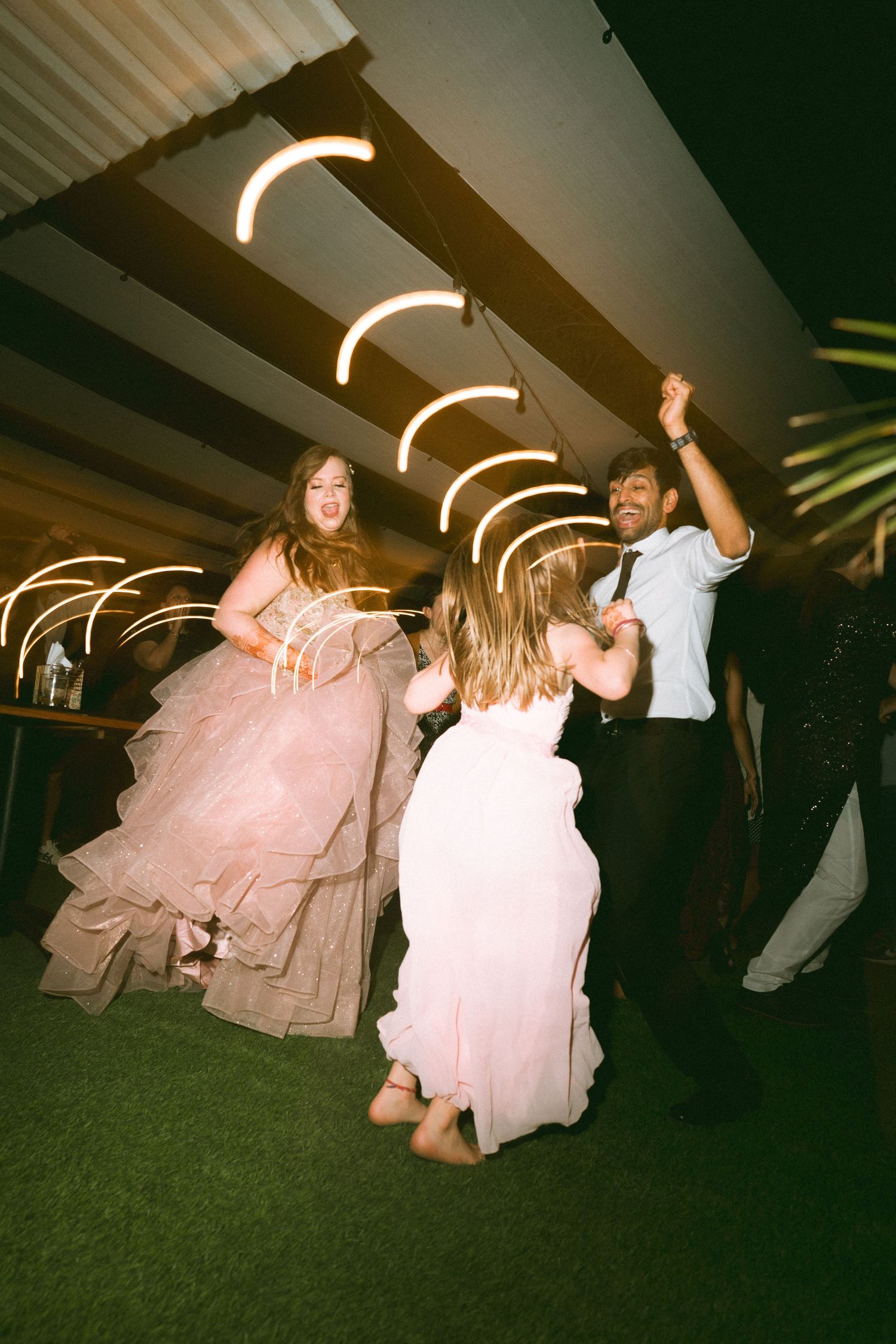 Celebratory wedding dance under curved ceiling lights with guests in formal attire by a wedding photographer in Sydney, Gold Coast & Brisb