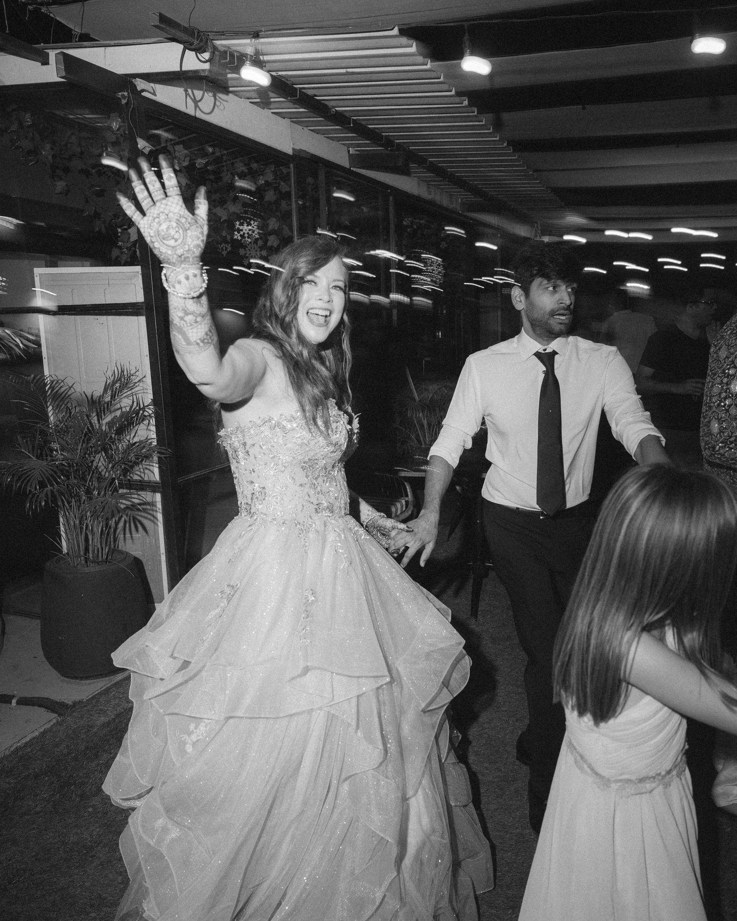Black & white capture of enthusiastic wedding dancing at an indoor venue by a wedding photographer in Sydney, Gold Coast & Brisbane.