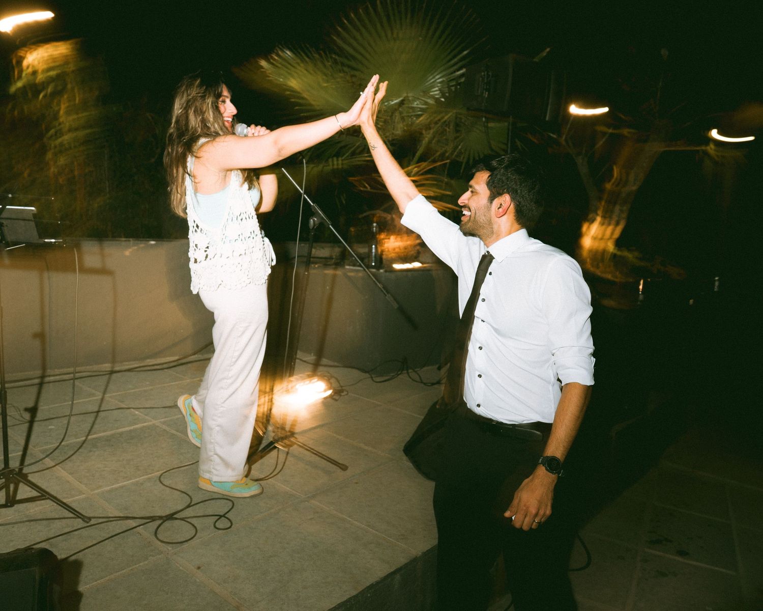 Wedding guests dancing and celebrating at a nighttime outdoor party under lights by the best wedding photographer in London.