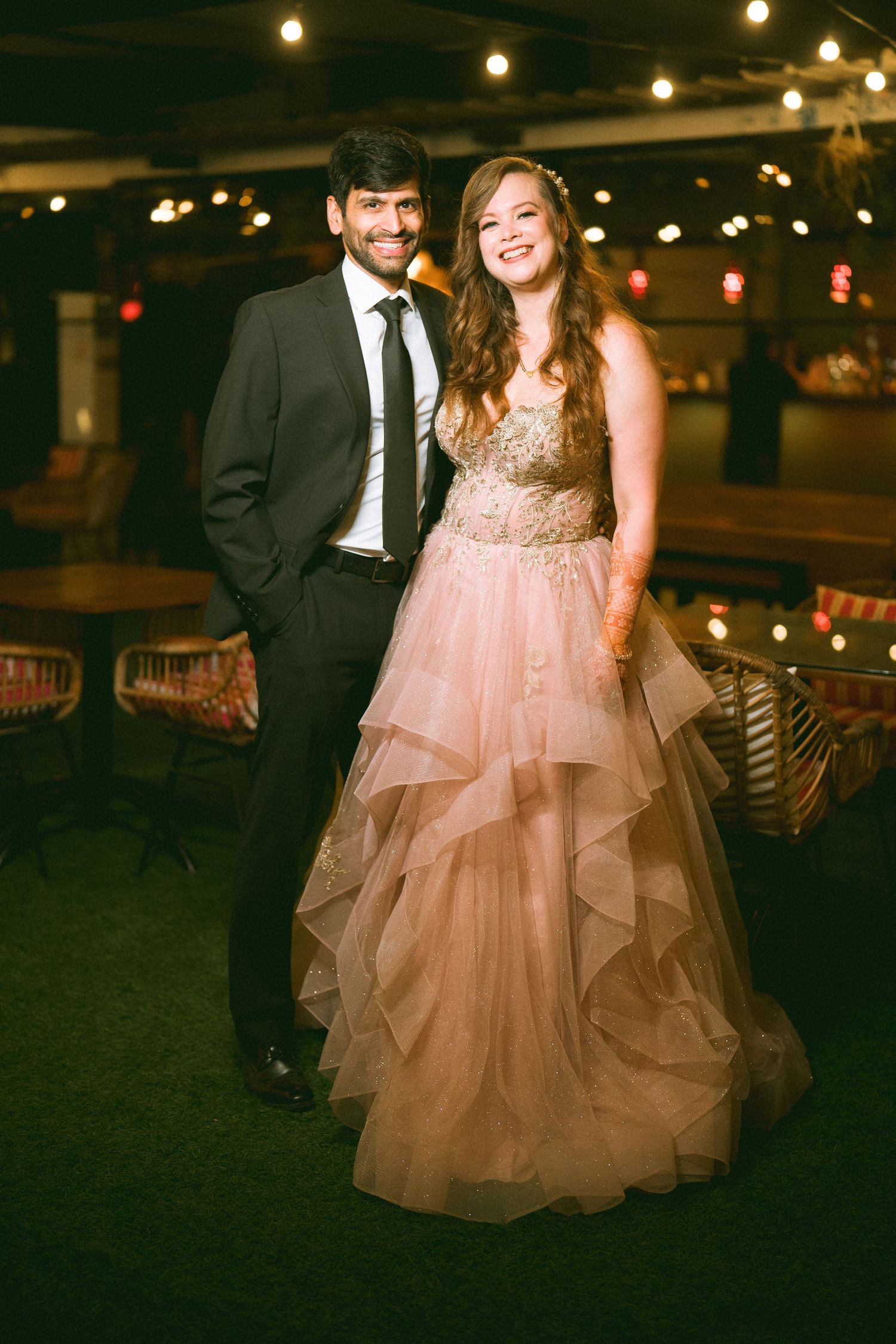 Couple dancing under string lights at night with bride in a flowing pink gown by the best wedding photographer in London.