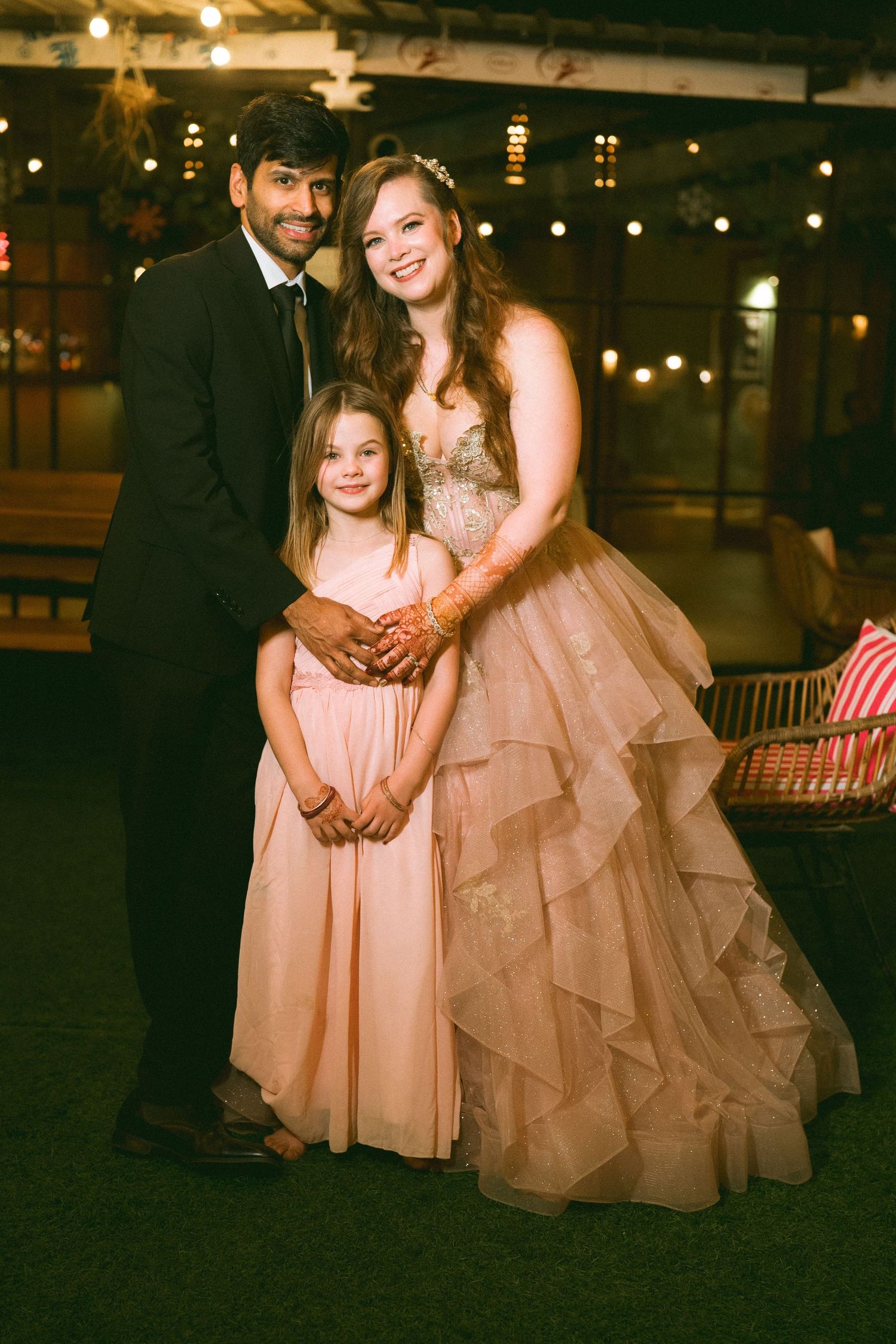 Wedding party in formal attire posing at an evening reception with twinkling lights by the best wedding photographer in London