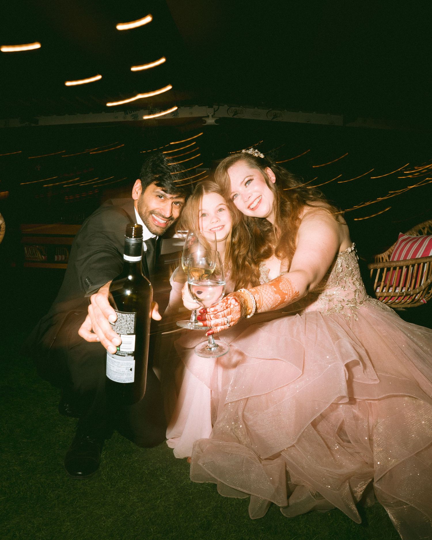 Wedding guests sharing drinks and laughter at a nighttime reception under string lights by the best wedding photographer in London