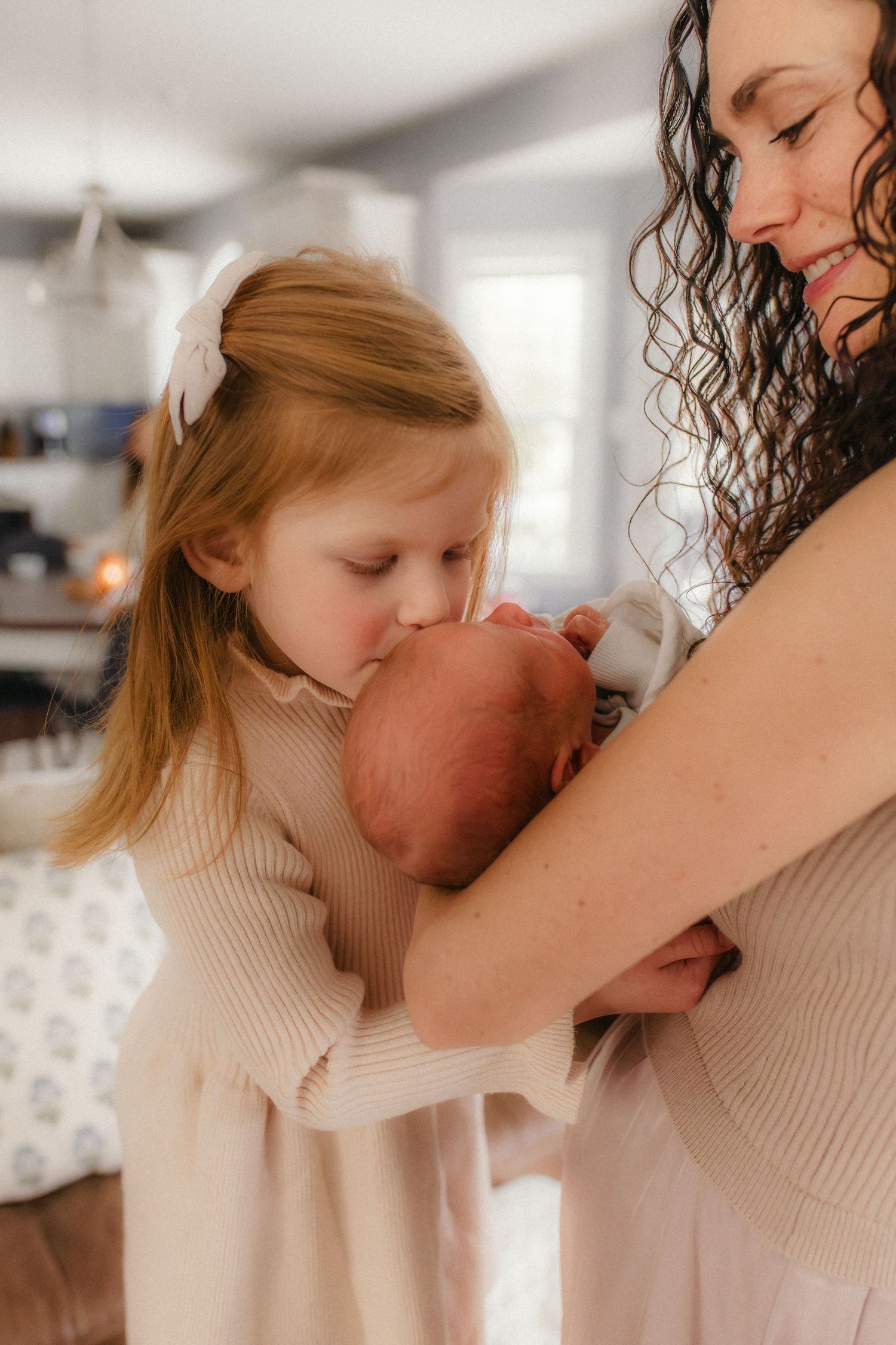 A tender moment captured in soft natural light as a newborn baby receives loving attention from family members.