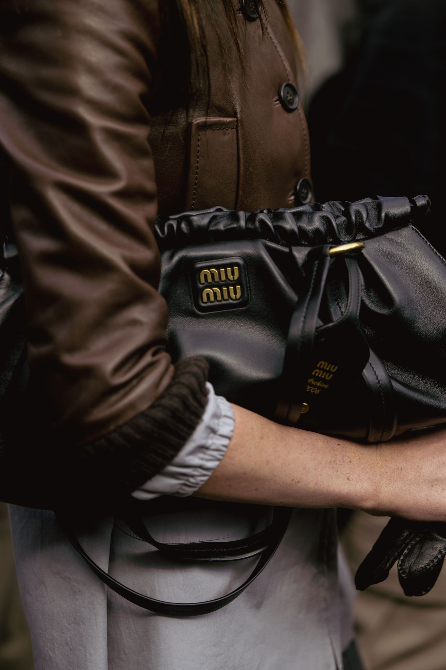 Close-up of black leather Miu Miu handbag with gold hardware details.