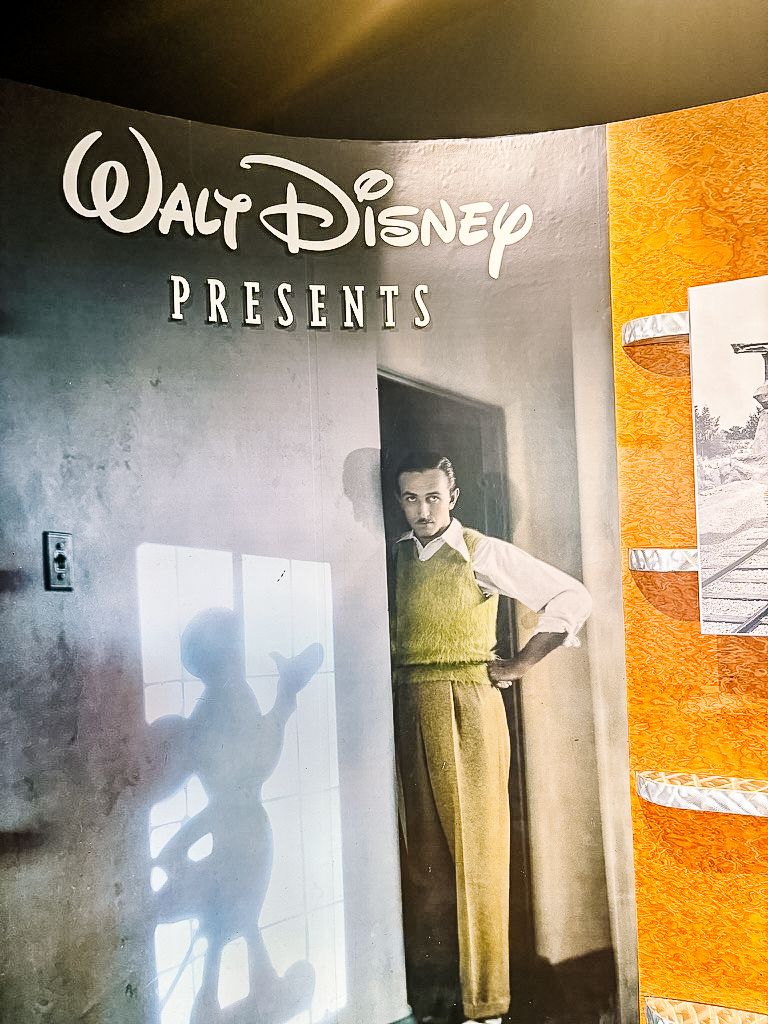 A retro Walt Disney studio photograph showing a vintage Walt Disney Presents title card with moody lighting and orange tones.