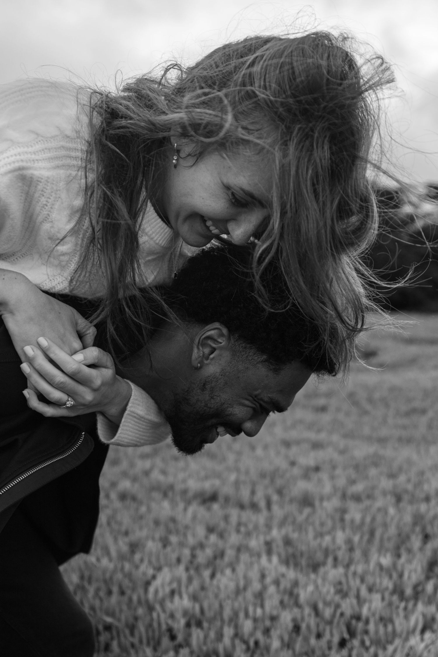 A joyful black and white portrait of a couple sharing an intimate moment together in a wheat field.