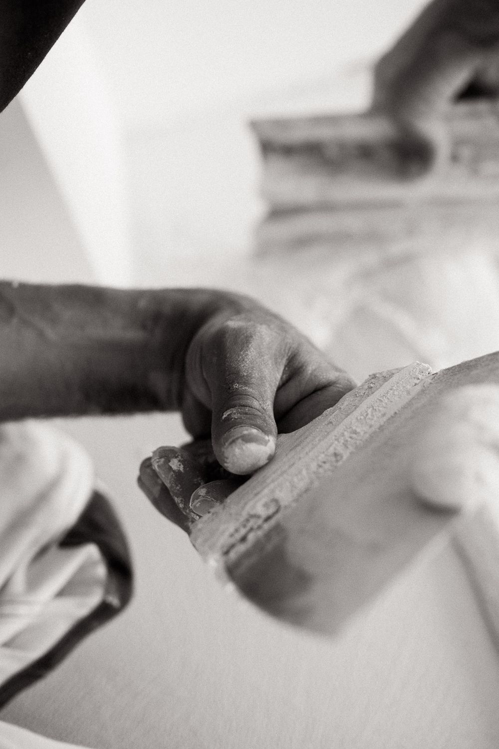 Close-up of hands using plastering tools during wall finishing.