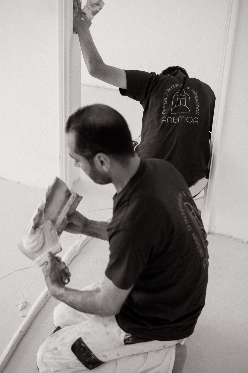 Workers applying plaster to interior walls during renovation.