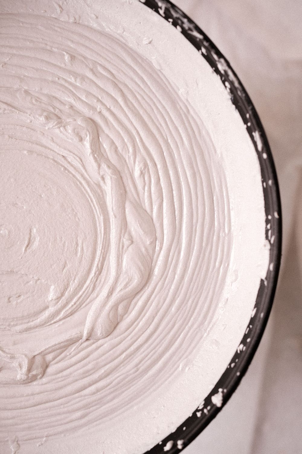 Close-up view of smoothly spread white frosting or plaster in a circular pattern.