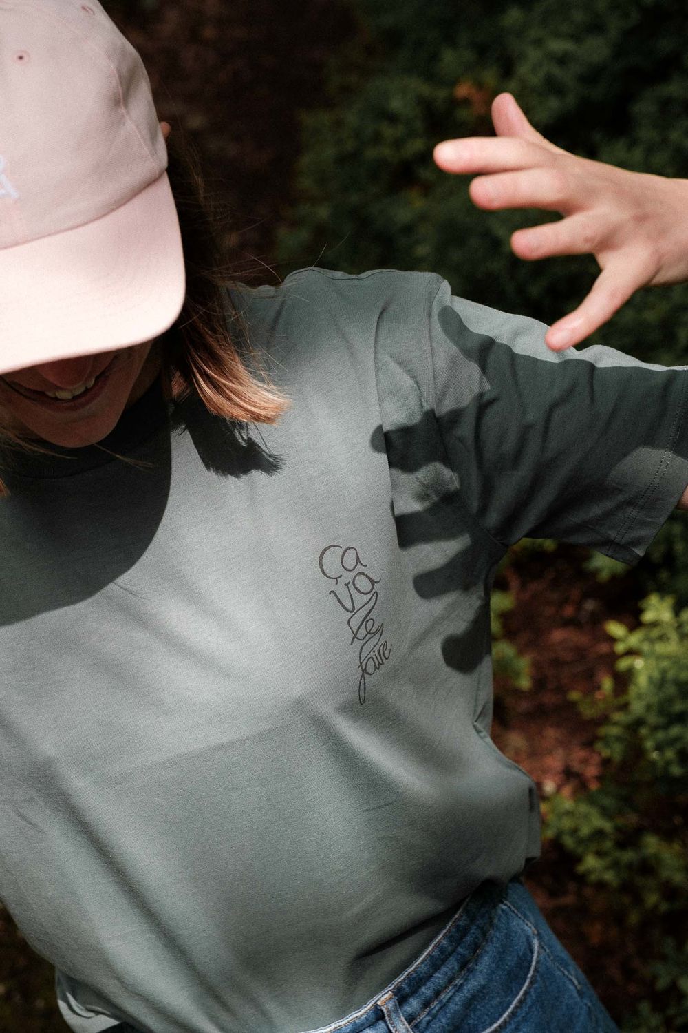 Detail shot of a gray t-shirt with small embroidered design and pink baseball cap.
