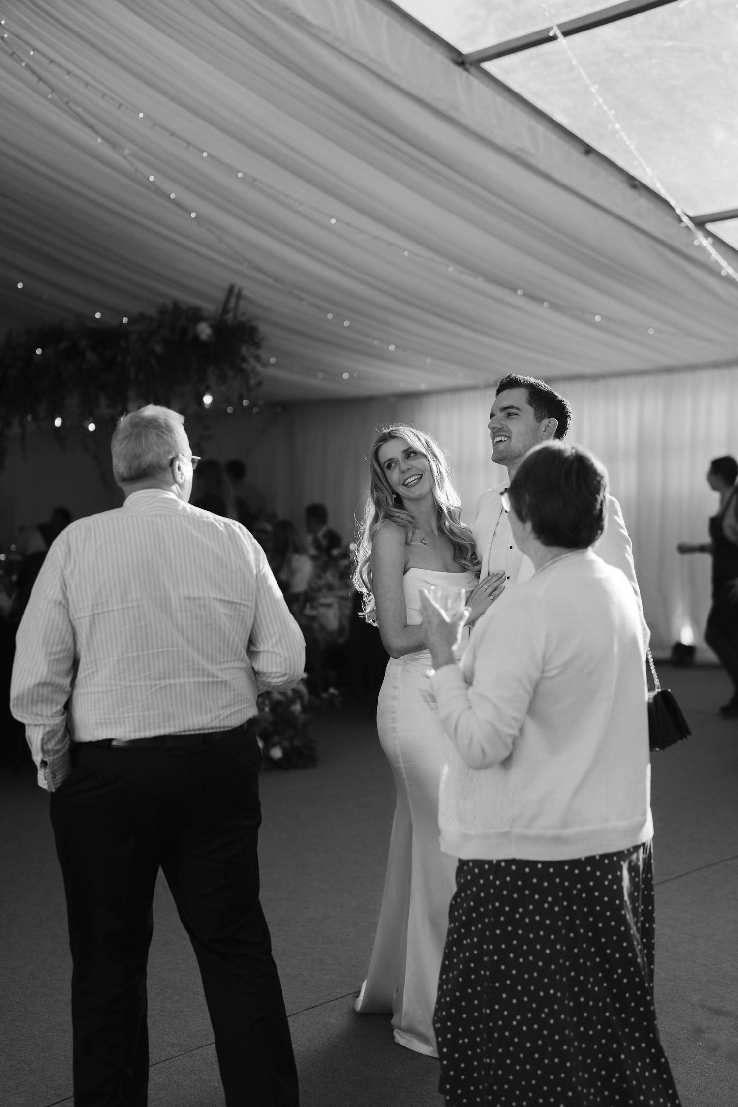 bride and groom smiling at each other, backlit by the sun coming through the marquee roof at hamswell house wedding in bath