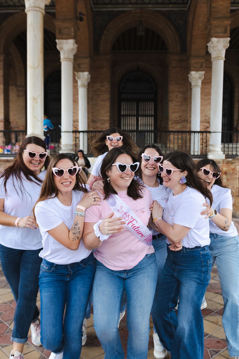 Portraits de groupe EVJF à 
Group wearing matching white t-shirts and jeans pose together with sunglasses at historic building with columns.