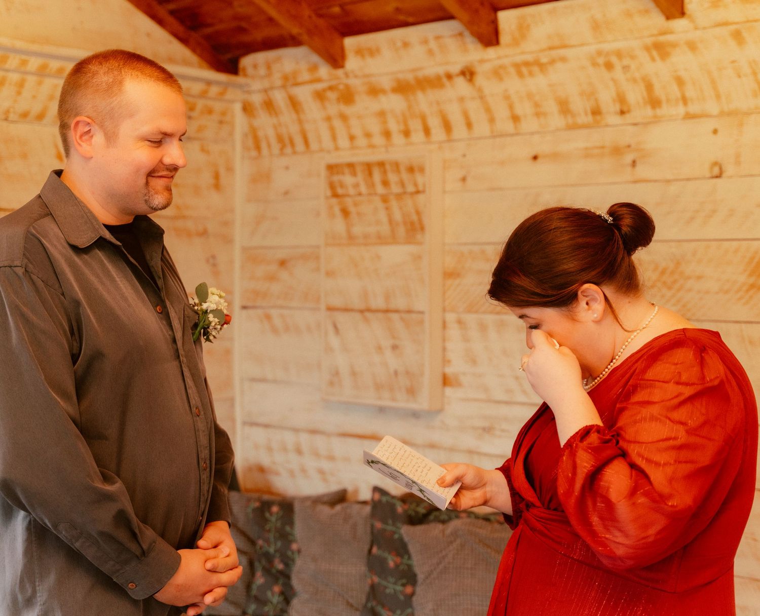 A couple sharing an emotional moment while reading letters in a rustic wooden room.