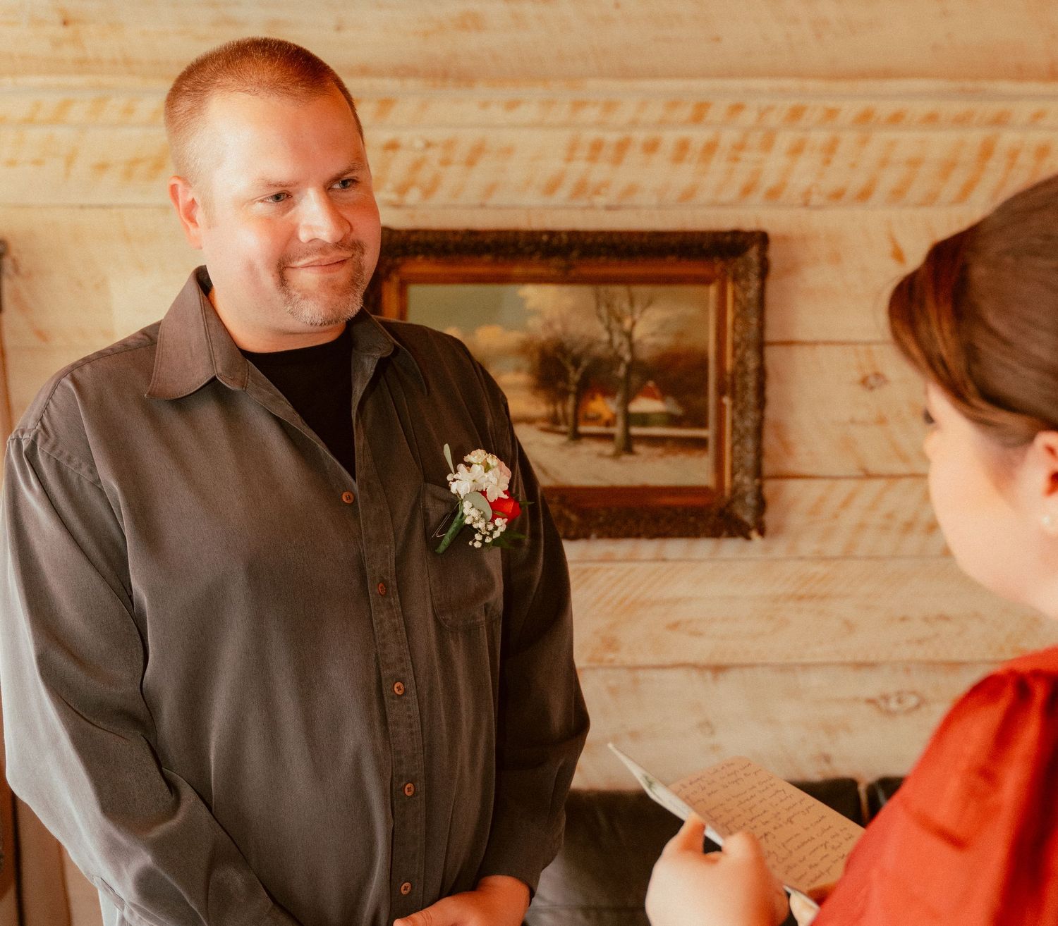 A couple exchanges wedding vows in a rustic wooden interior setting.
