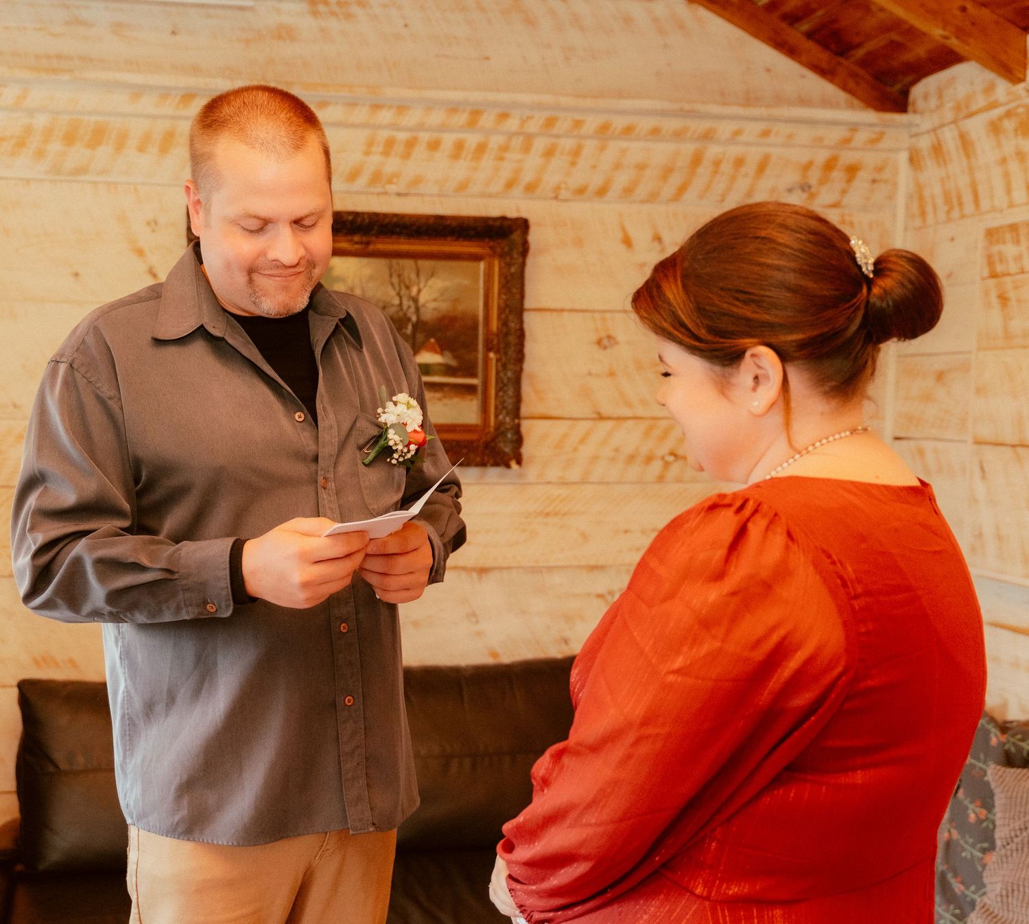 Couple examining decorative items together indoors with wooden walls and framed artwork in background.