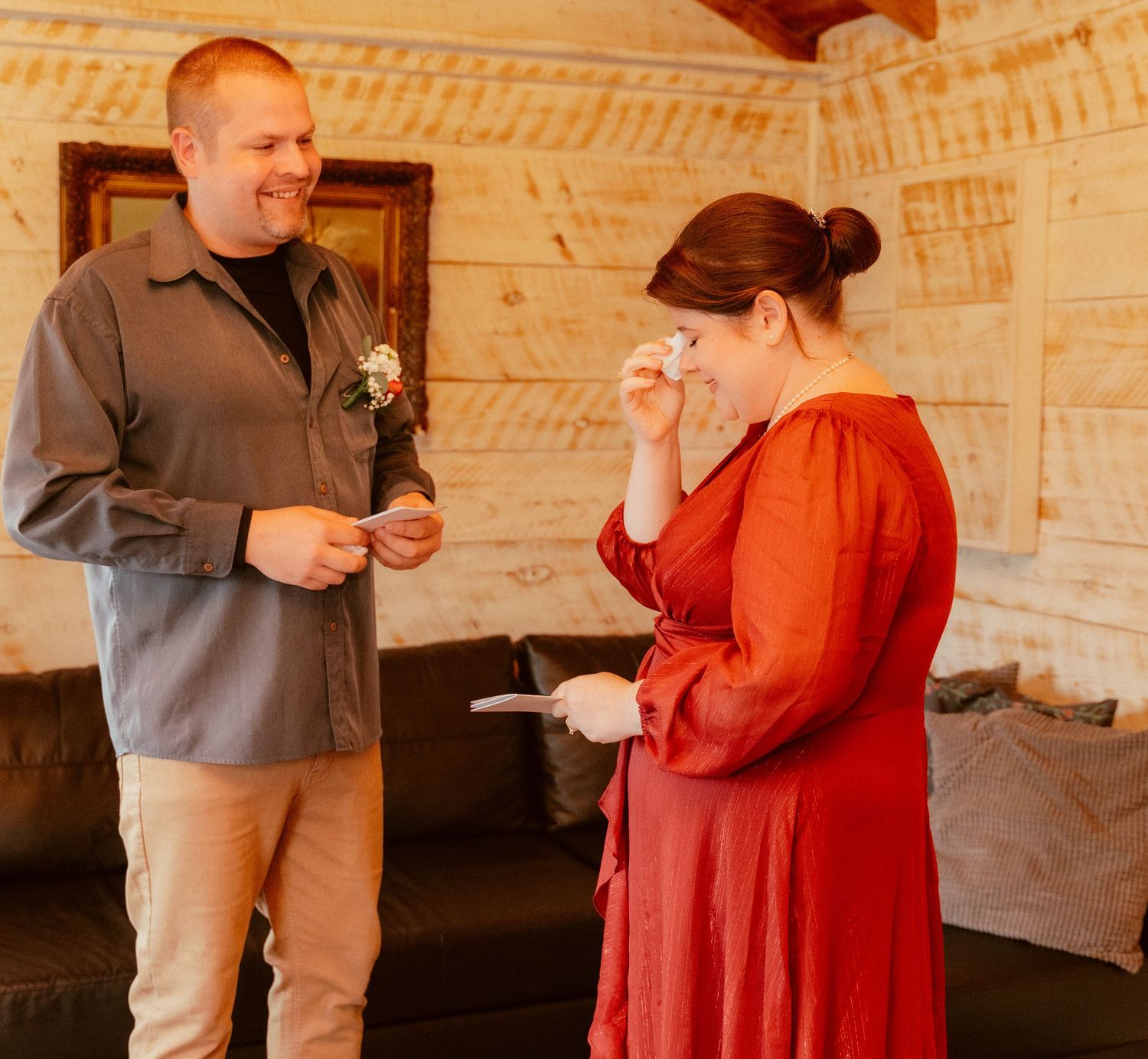 A couple shares an intimate moment in a rustic cabin room decorated with wooden walls and a hanging landscape painting.
