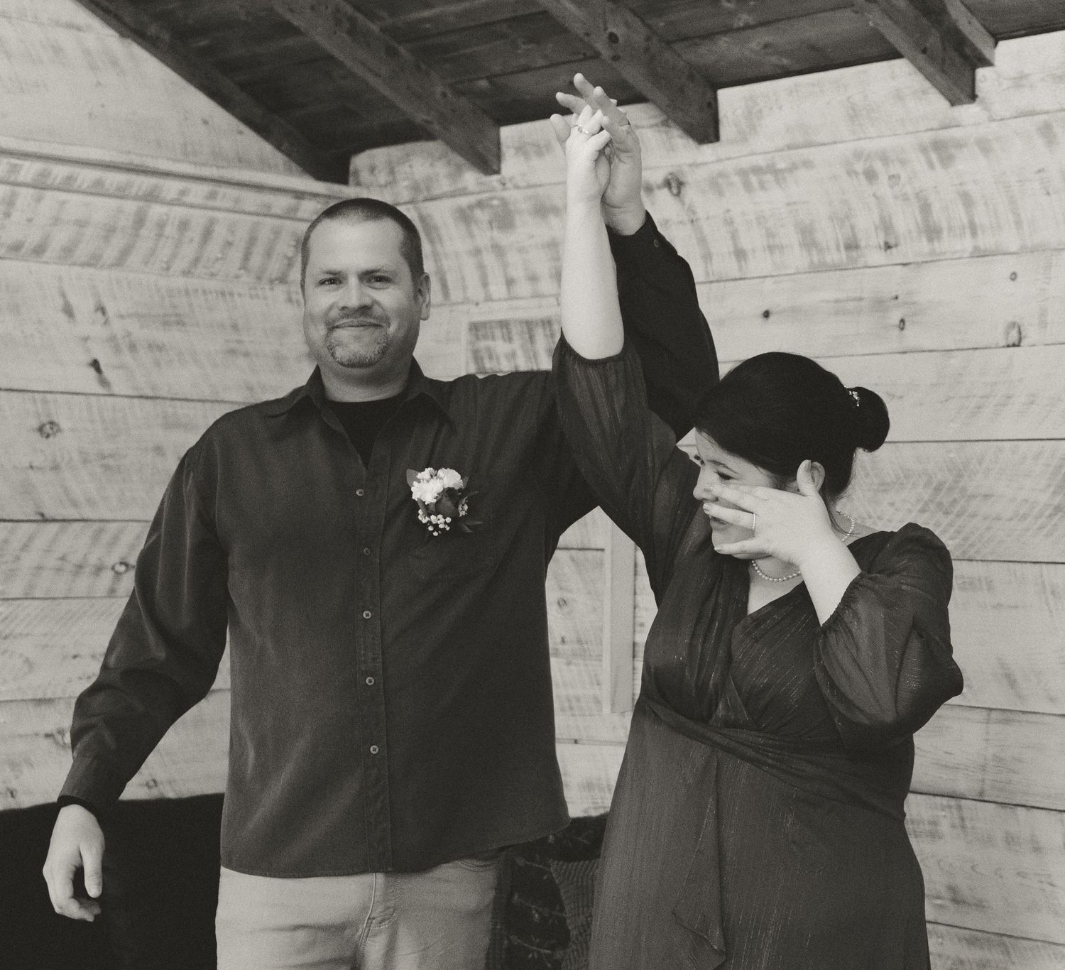 A joyful celebration captured in black and white as a couple raises their joined hands.