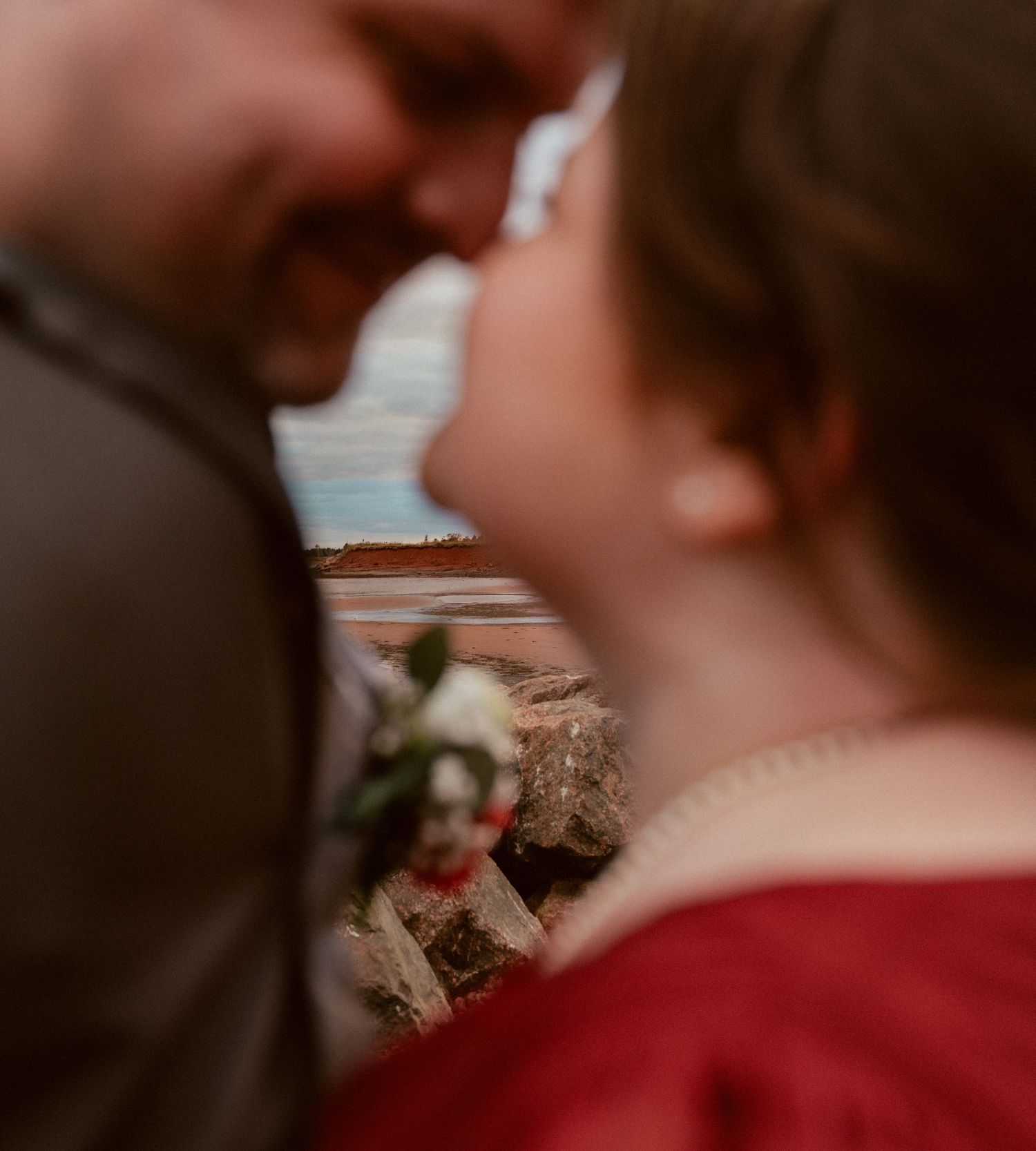 An intimate close-up portrait capturing a tender moment by the coast.