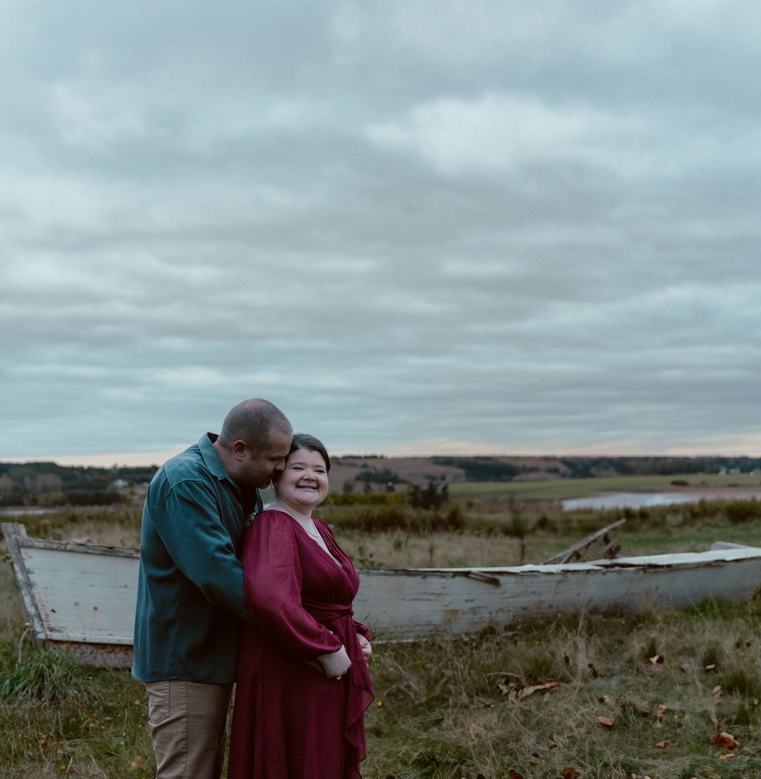 A couple embraces on a misty coastline during their wedding photoshoot.