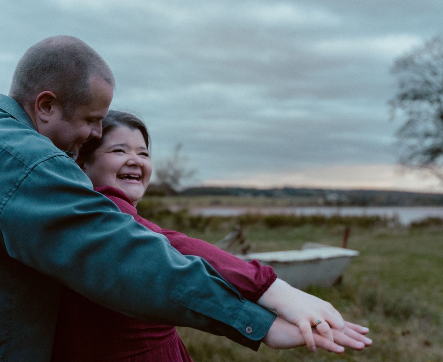 A playful moment shared between a couple by the water at dusk.