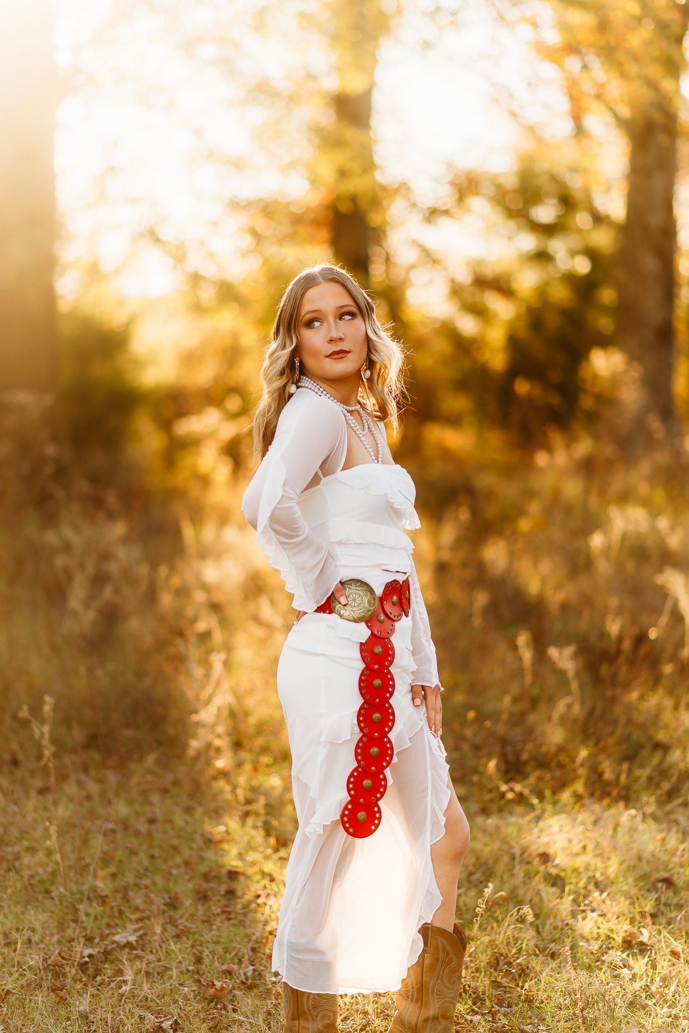 White dress with red floral details photographed in golden sunset light.