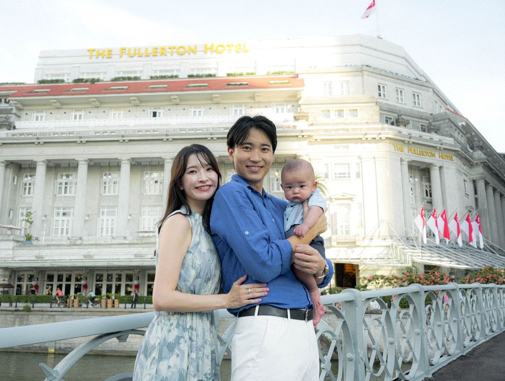Happy family portrait against the colonial architecture of Fullerton Hotel Singapore.