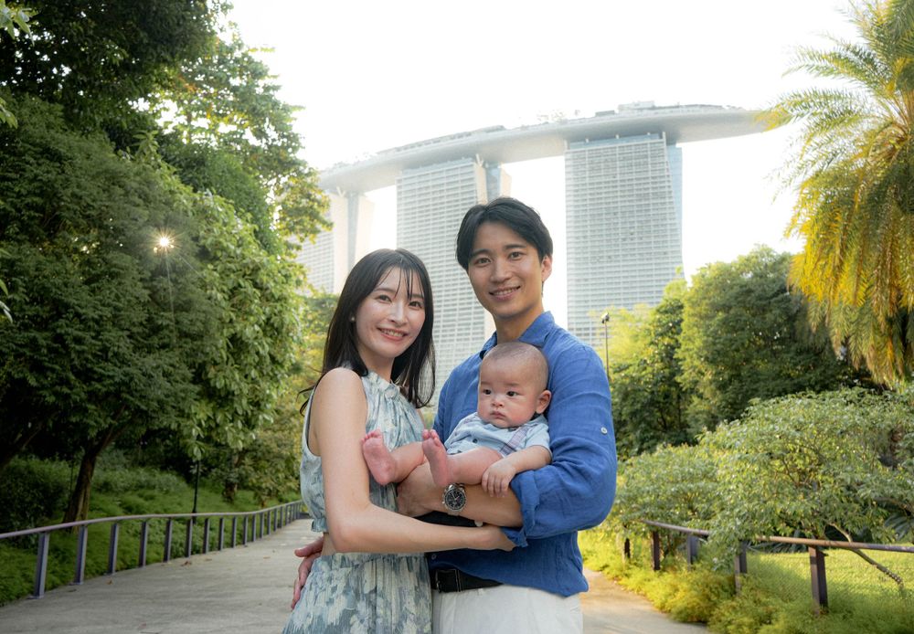 Family portrait in lush gardens with Marina Bay Sands towers in background.