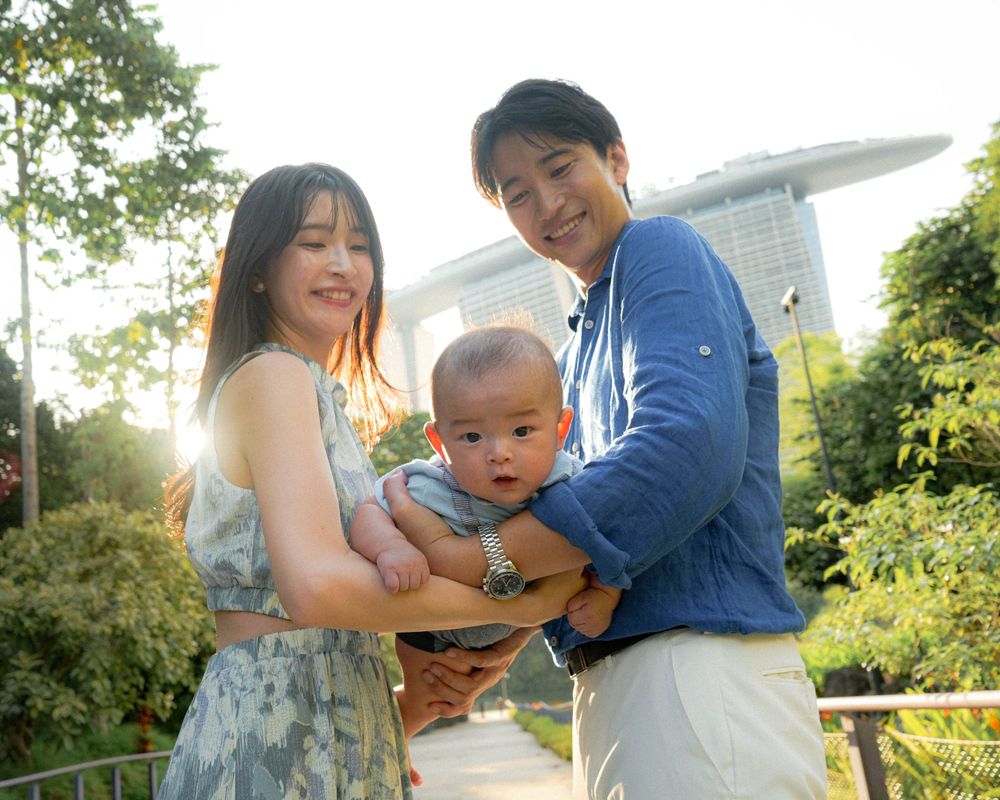 Family portrait captured at Gardens by the Bay with iconic Singapore hotel architecture in background.