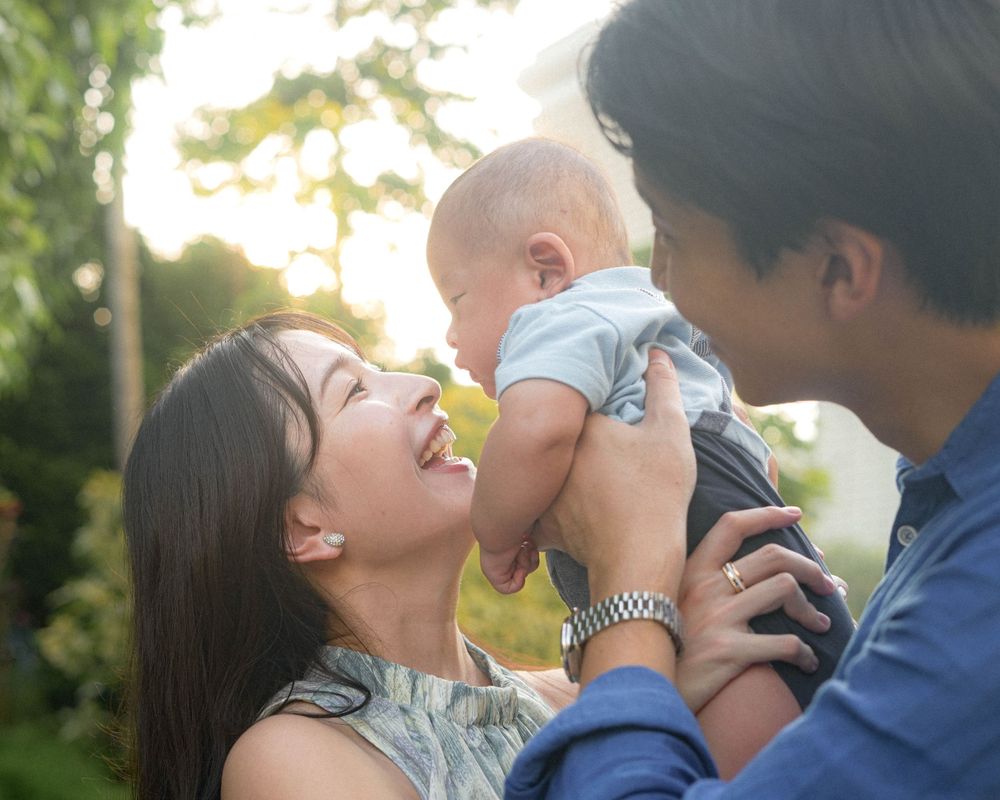 Joyful family moment with baby against Singapore skyline during golden hour.