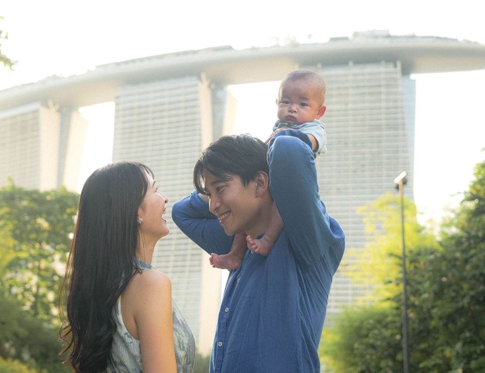 Parent lifts child onto shoulders during sunset at Gardens by the Bay Singapore.