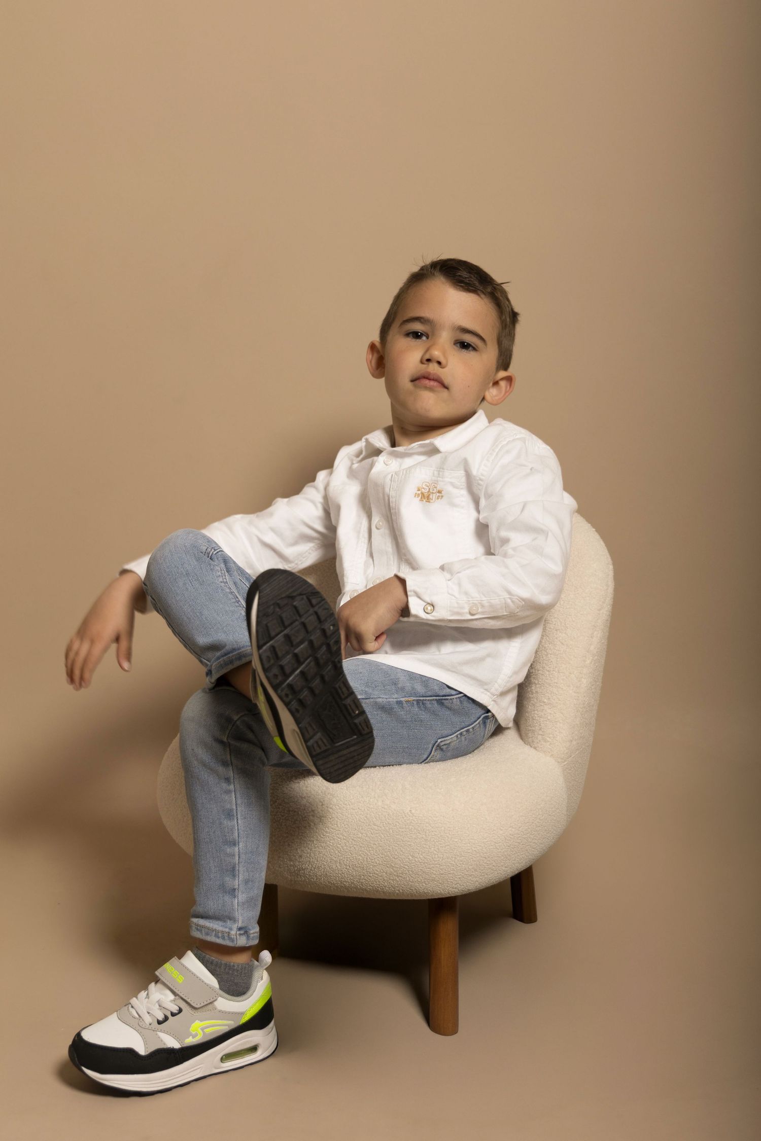 Séance photo d'un petit garçon sur fond beige en studio