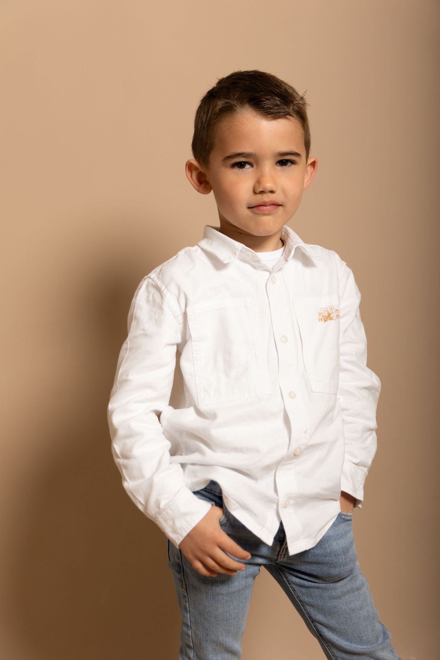 Séance photo d'un petit garçon sur fond beige en studio