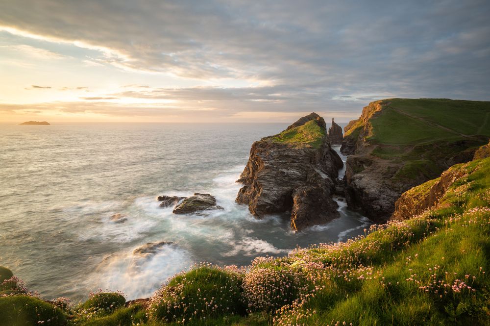 Dramatic coastal cliffs and crashing waves at sunset along Cornwall's rugged coastline near Bedruthan Steps.