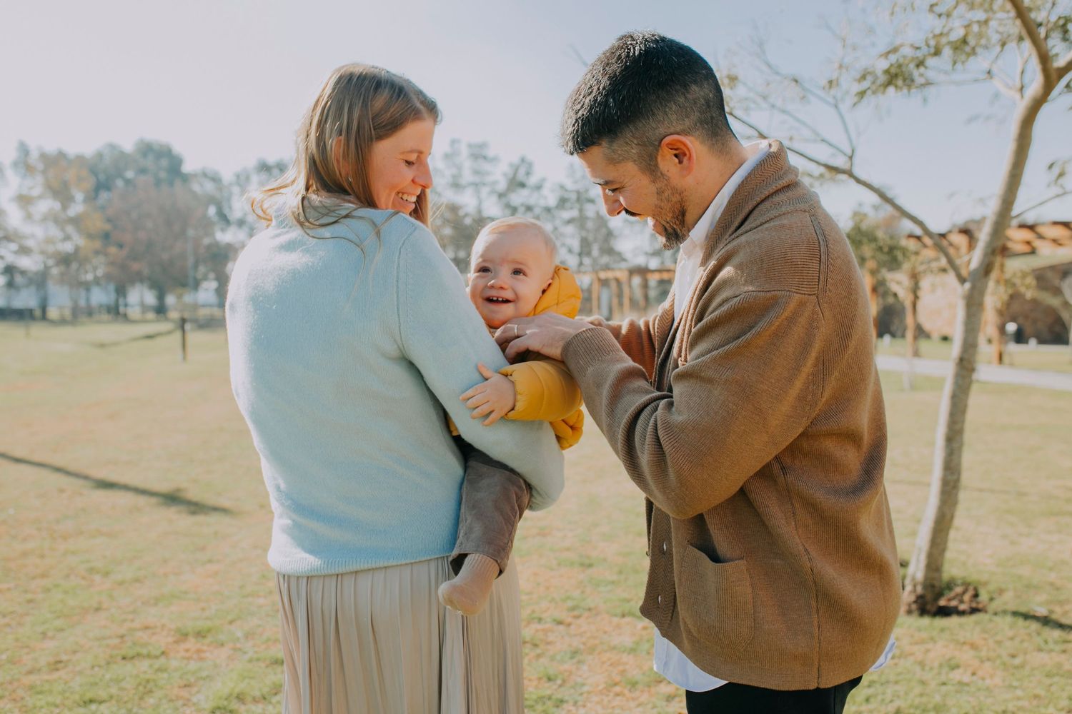 A family shares a joyful moment together while spending time outdoors in a park on a sunny day.
