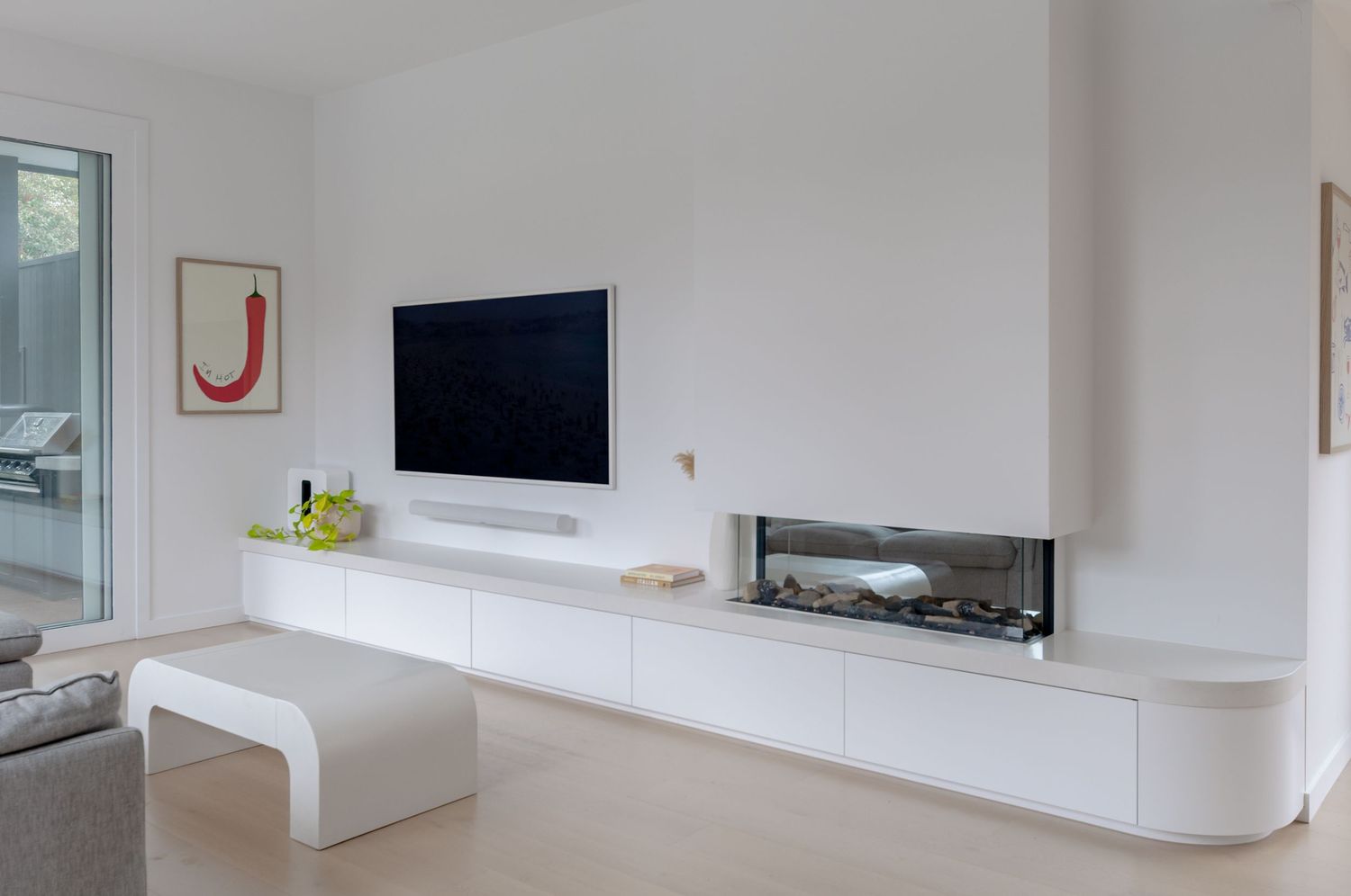 Sleek white entertainment unit with wall-mounted TV and built-in fireplace in a contemporary living space.