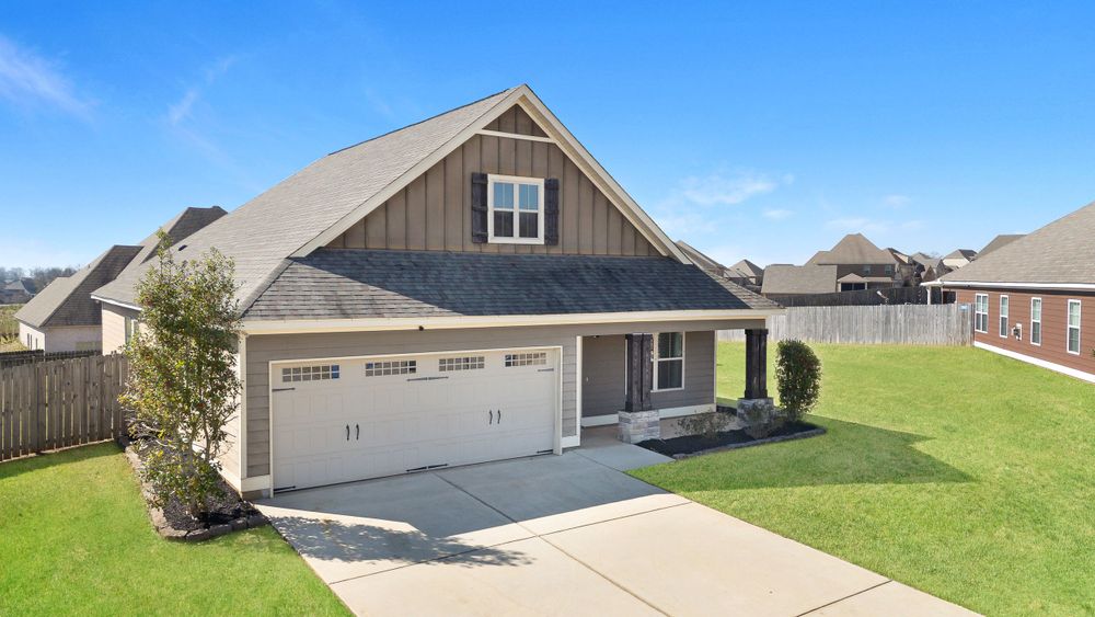 Craftsman style home with gray exterior, two-car garage and manicured lawn in residential neighborhood.
