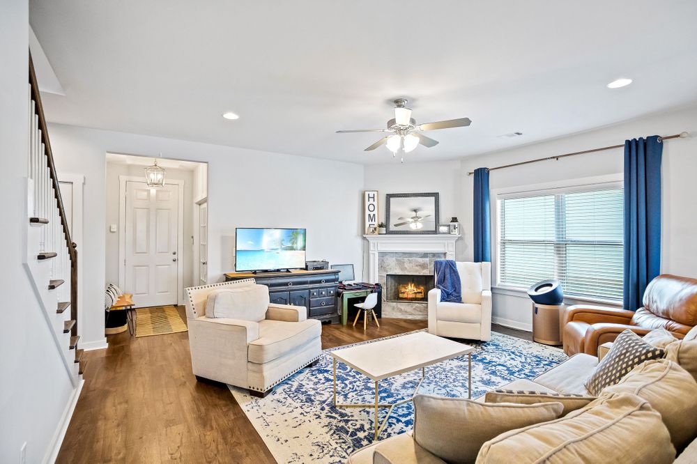 Bright living room with blue accents, white furniture, and hardwood floors featuring a modern coastal design.