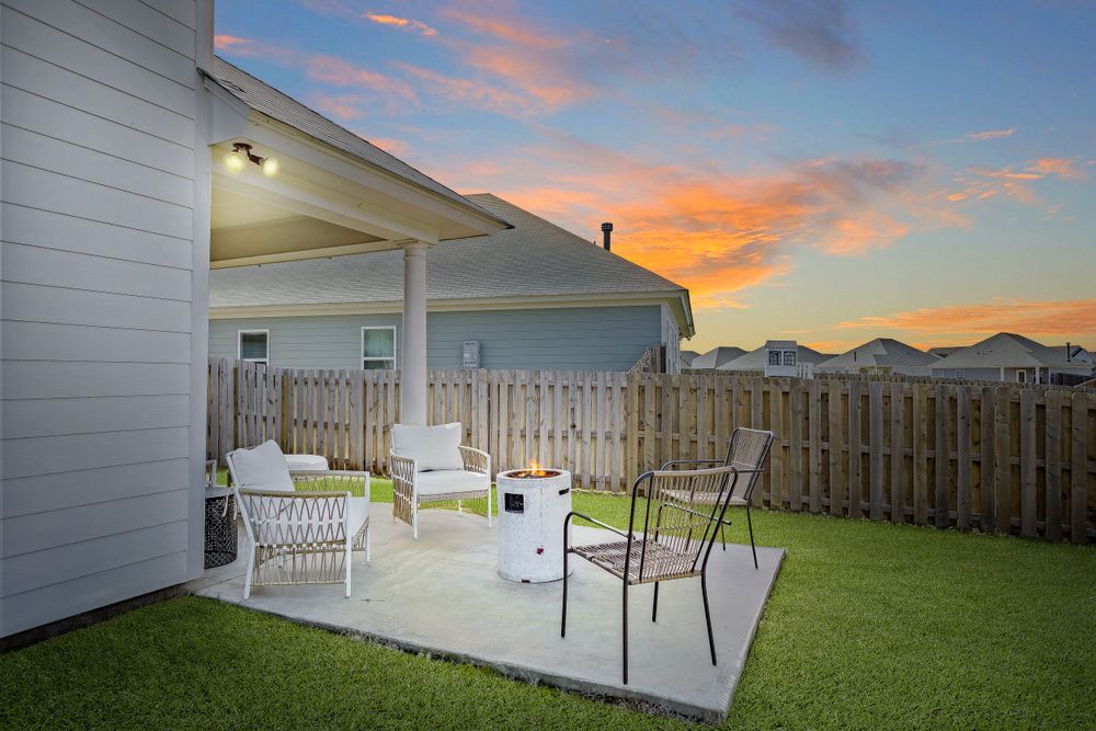 Cozy backyard patio with white furniture and fencing against a dramatic sunset sky.