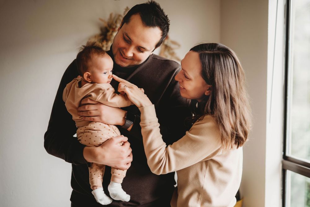 Family sharing an intimate moment together near a bright window.