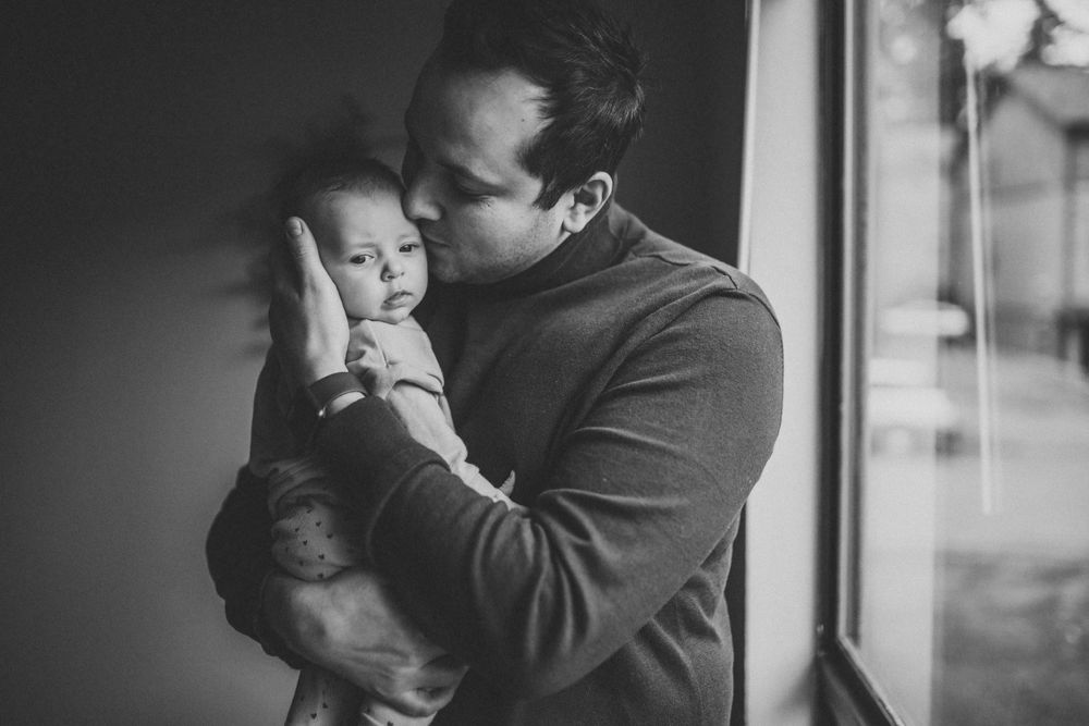 Monochrome portrait capturing a gentle embrace with an infant.