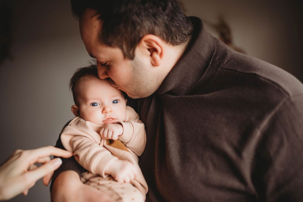 Close-up of a sweet bonding moment with a baby wearing a pacifier.