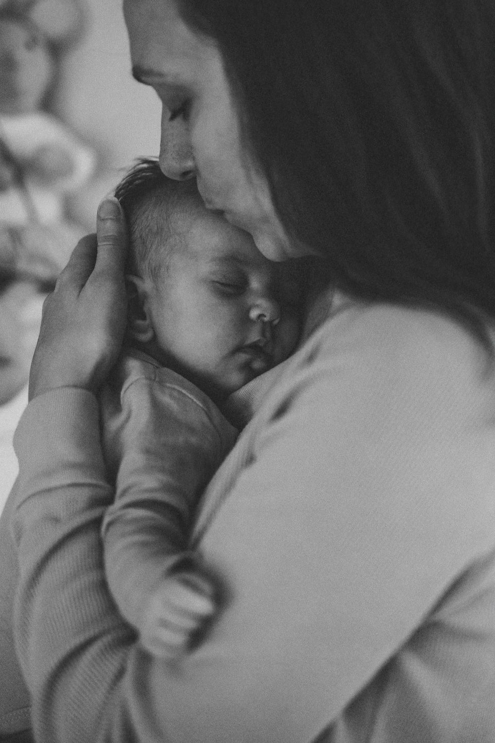Black and white intimate portrait of a sleeping baby being cradled.